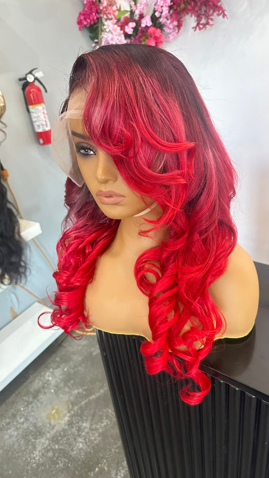 Human hair wig that is primarily a ruby red color with darker roots; front right quarter view.