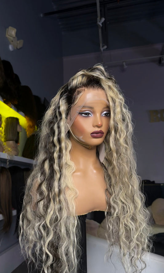 Human hair wig with a blonde color as a base, with jet black roots and streaks.