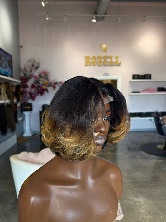 Short wig with dark roots and yellow highlights on the bottom half; left side view.