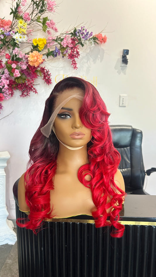 Human hair wig that is primarily a ruby red color with darker roots; front view.