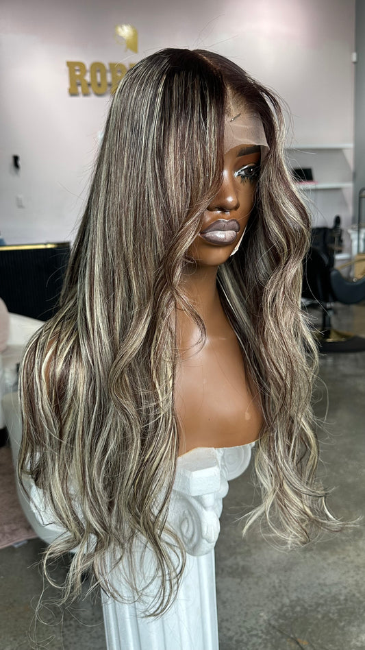 Medium length wig with dark roots and white highlights.