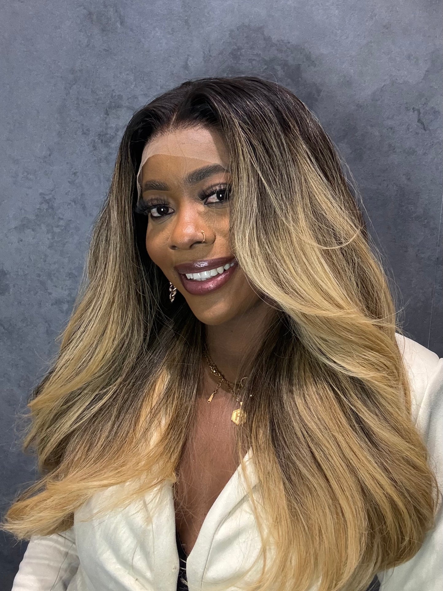 Woman with long, wavy hair transitioning from black to blonde against a gray background