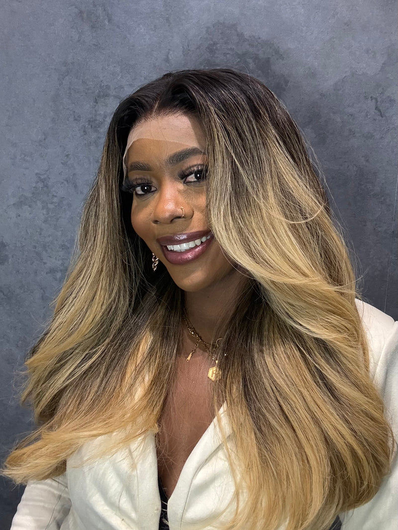 Woman with long, wavy hair transitioning from black to blonde against a gray background