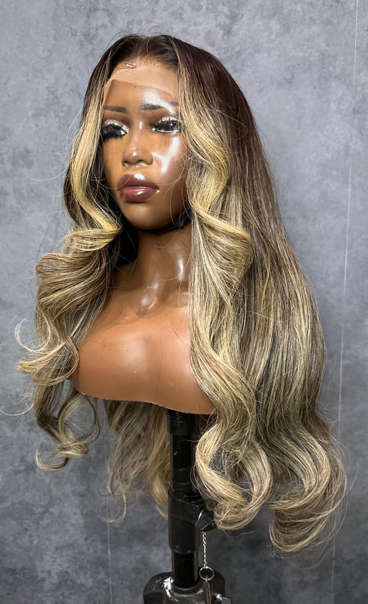 Mannequin head with long, wavy, blonde raw Indian hair wig against a gray background.