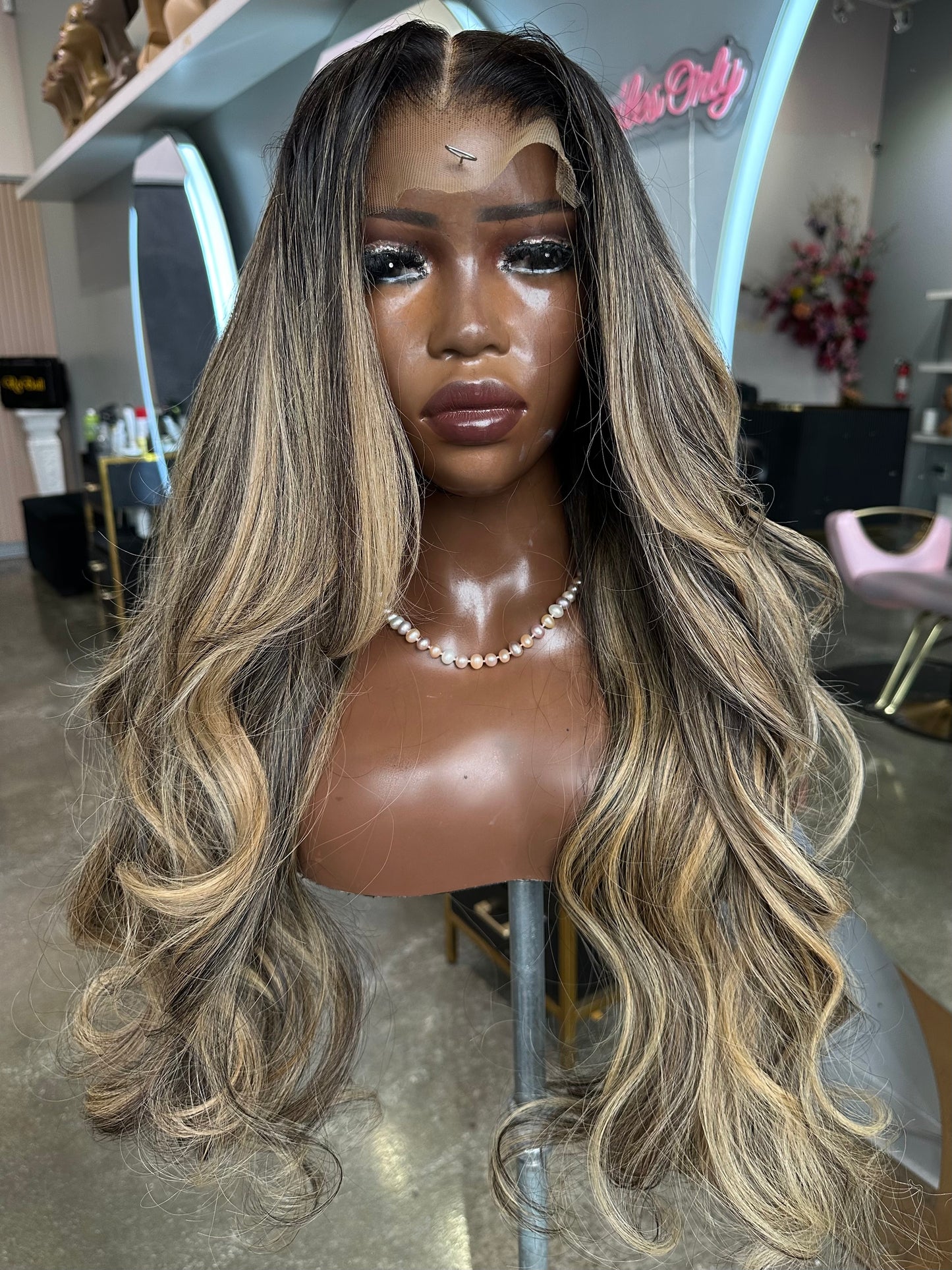 Mannequin head with a long, wavy, two-tone wig in a salon setting.